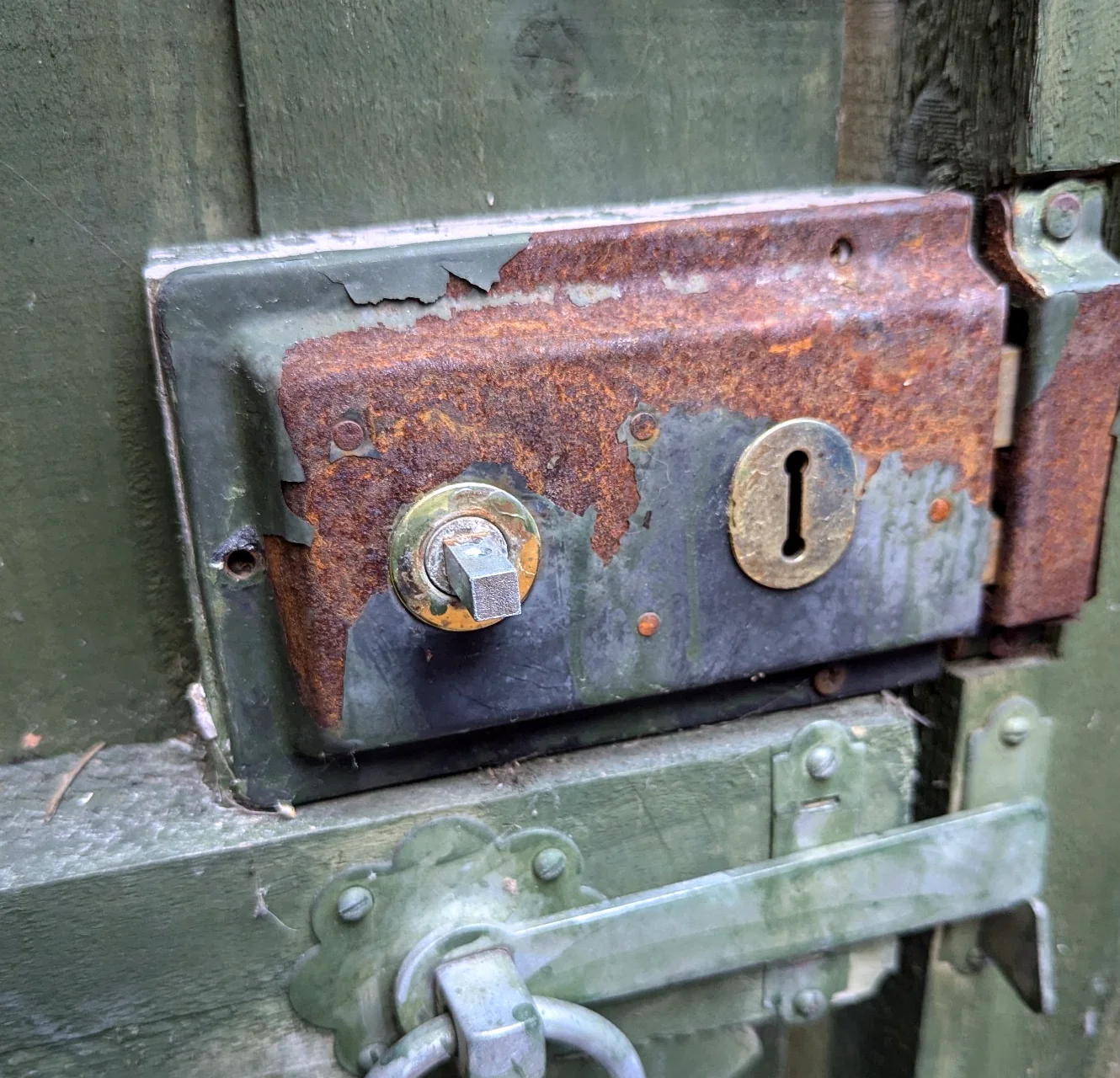 Corroded old surface mounted lock on a green timber gate before upgrade