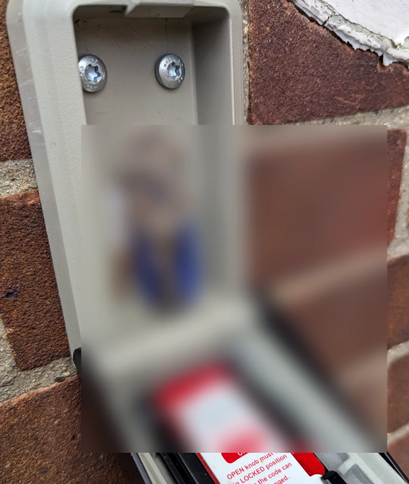 Wall-mounted key safe with sensitive key and code details obscured