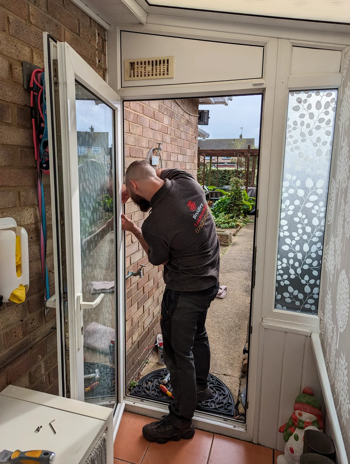 Brodley Locksmiths carrying out locking work on a white uPVC door